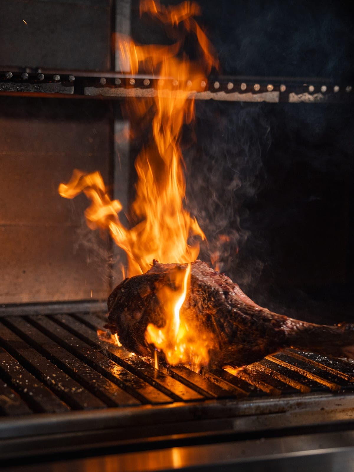 Flames rising around a steak on the grill