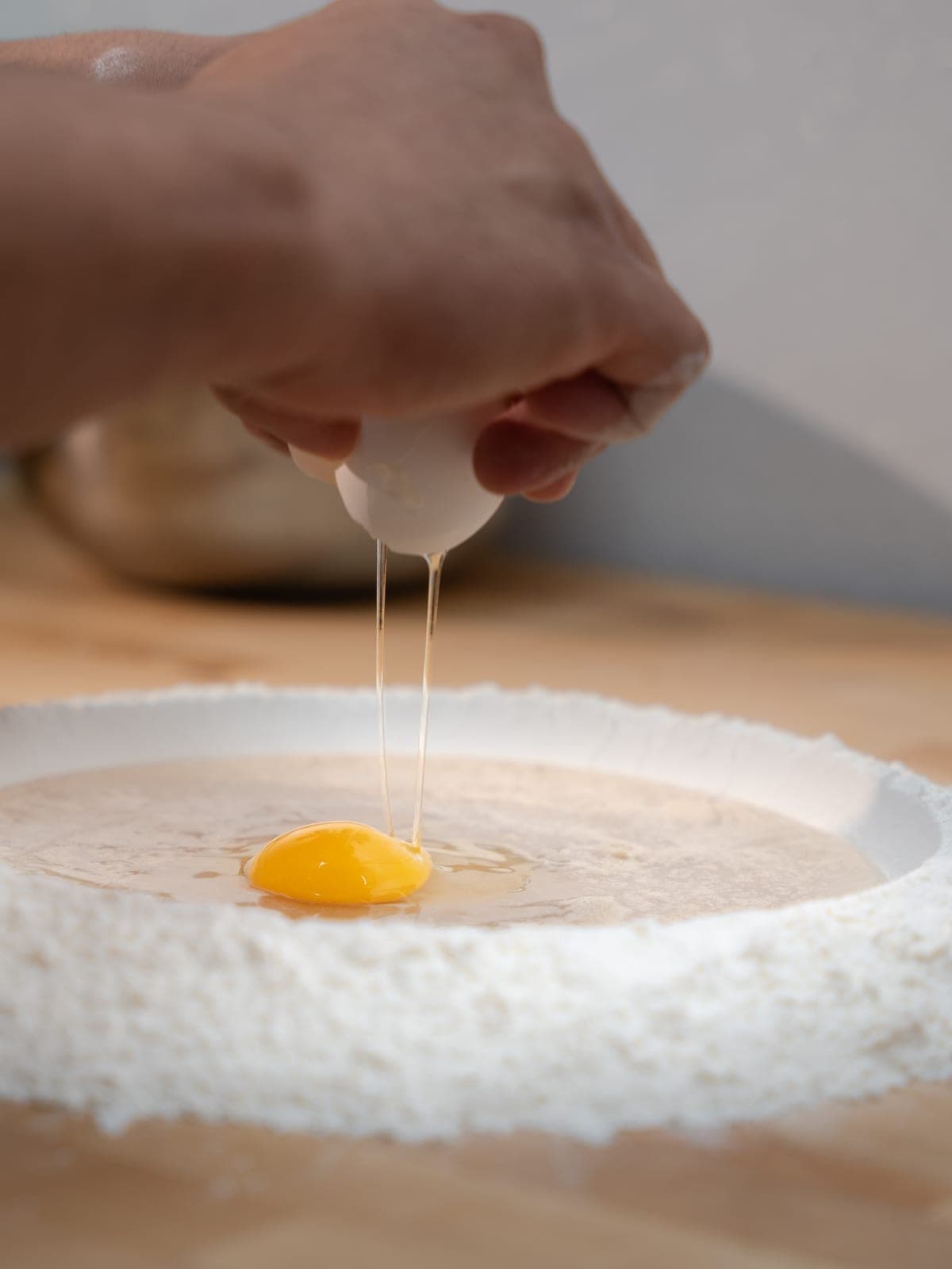 An egg cracked into a well of flour