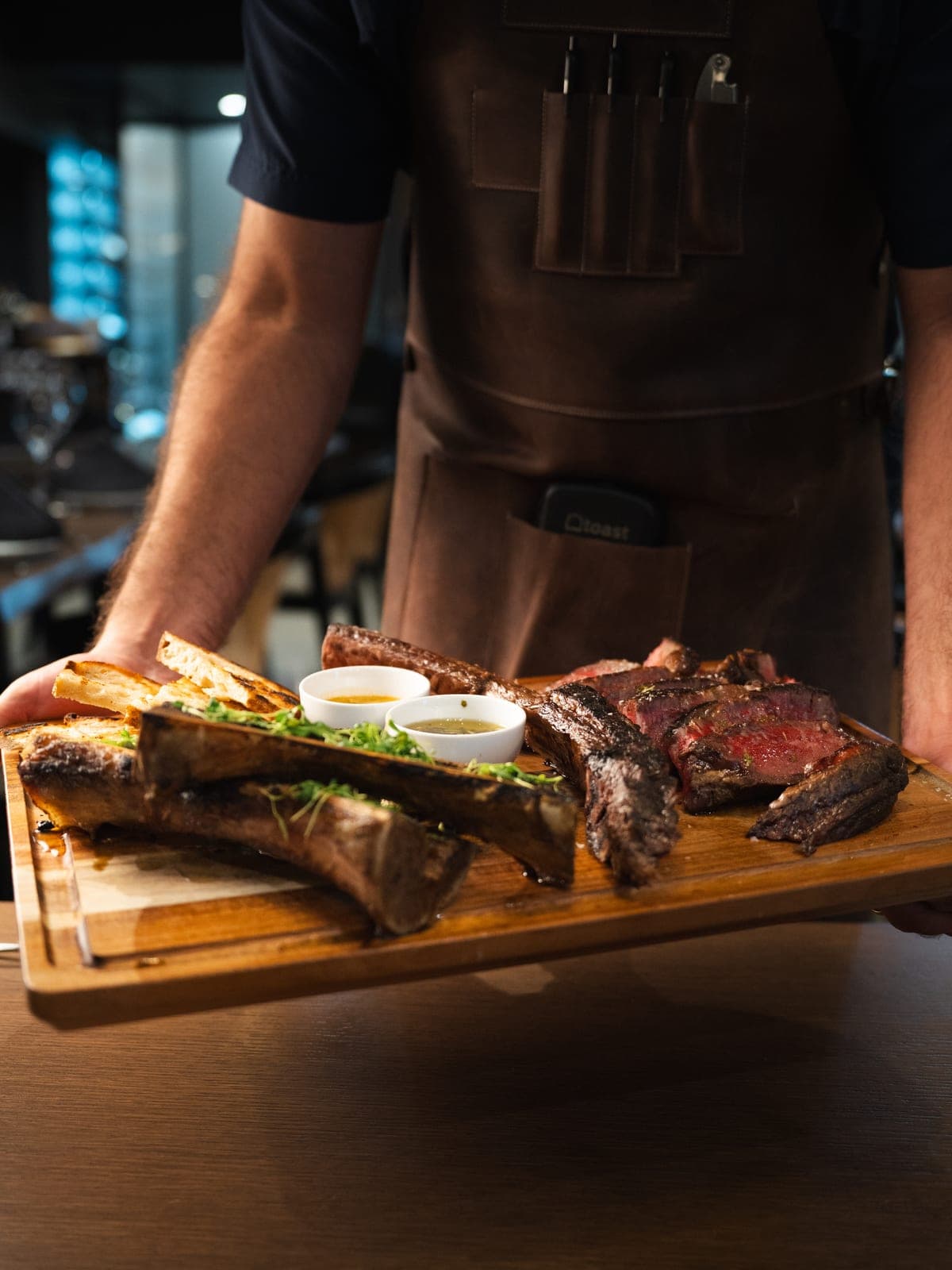 A board of grilled steak carried to the table