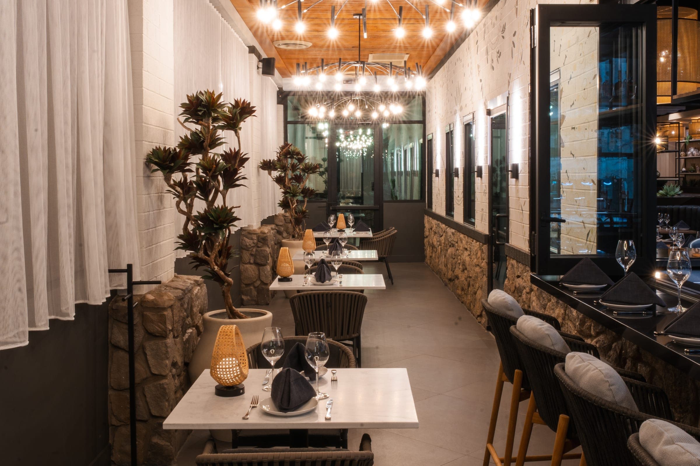 A dining corridor with chandeliers and plants